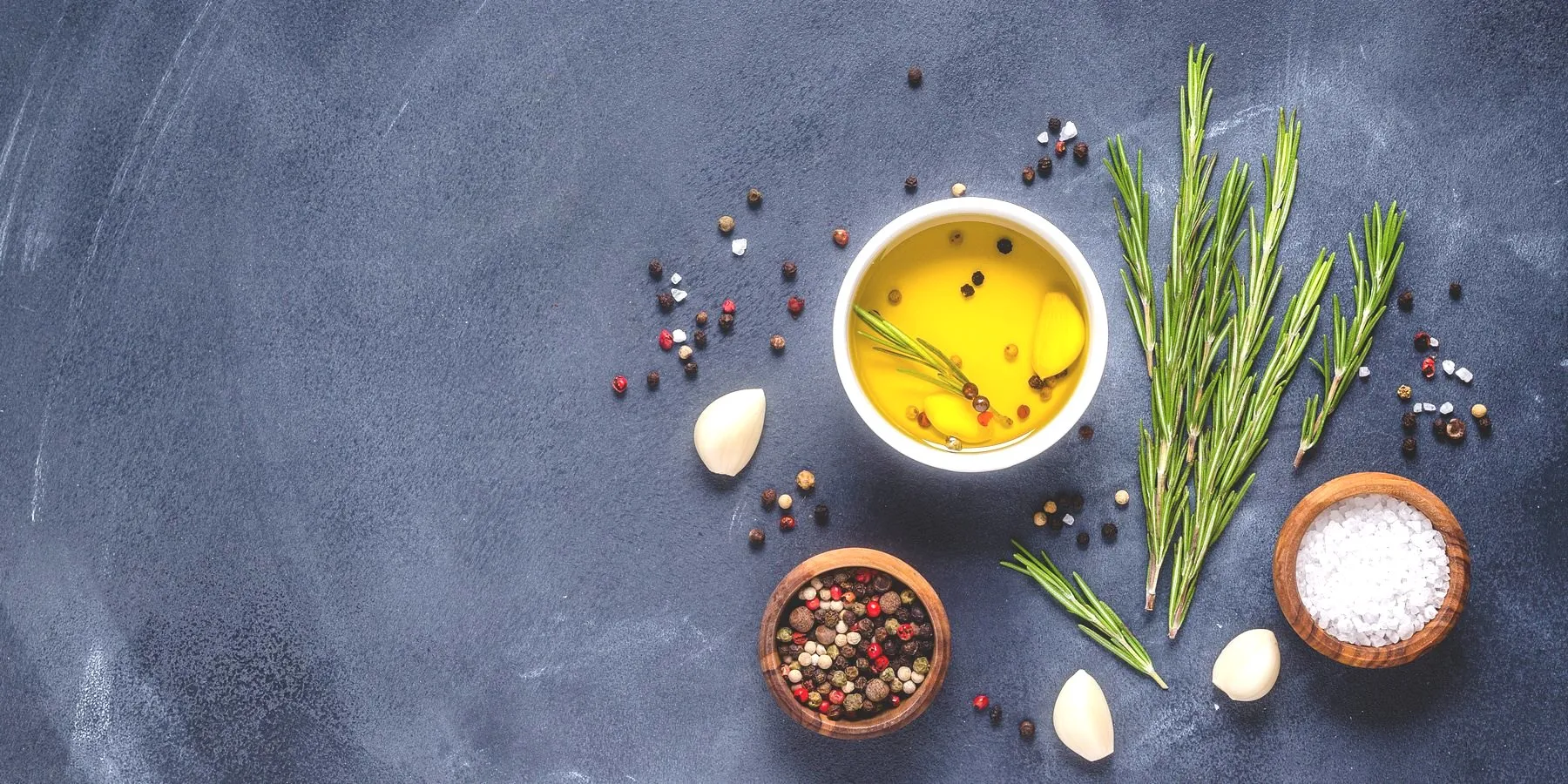 Minyak olive dan herba segar di atas batu gelap