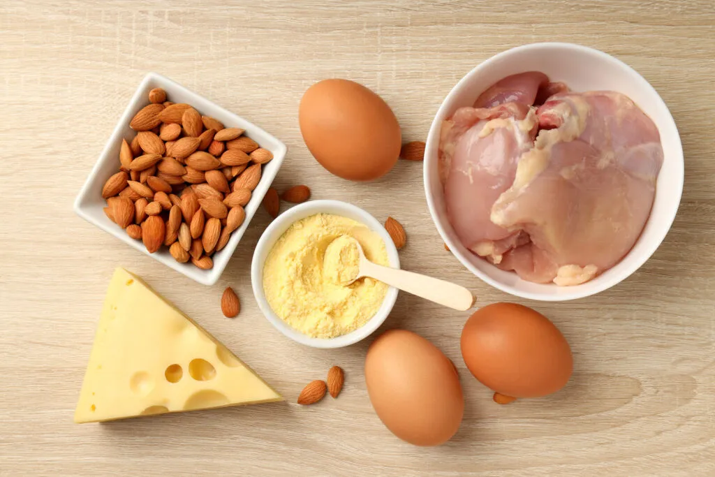 Telur, dada ayam, badam dan keju di atas papan kayu, sumber protein yang menghalang kehilangan otot pada terapi GLP-1