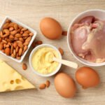 Telur, dada ayam, badam dan keju di atas papan kayu, sumber protein yang menghalang kehilangan otot pada terapi GLP-1