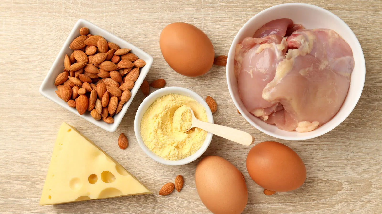 Telur, dada ayam, badam dan keju di atas papan kayu, sumber protein yang menghalang kehilangan otot pada terapi GLP-1