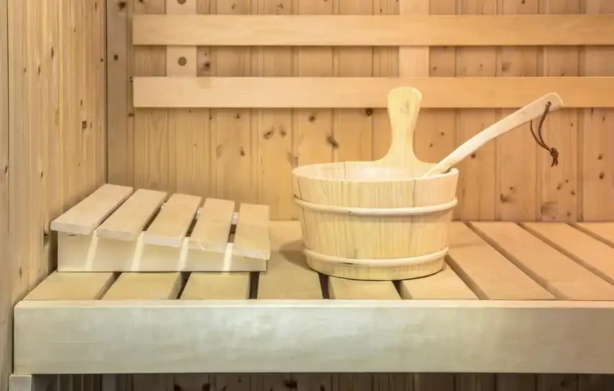 Baldi dan senduk kayu di atas bangku sauna berpanel kayu